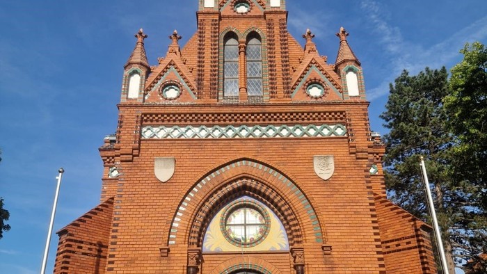 Eine charmante Backsteinkirche mit filigranen gotischen Architekturelementen und einem markanten Bogenportal.