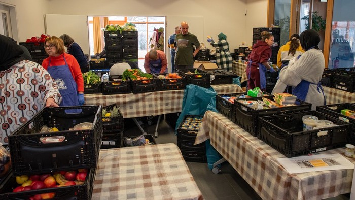 Helferinnen stellen Lebensmittel auf mehrere Tische.