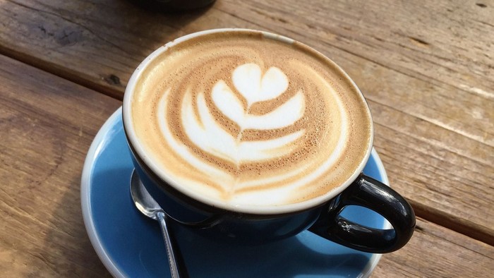 Eine Tasse Kaffee mit Milchschaumherz auf einem Holztisch