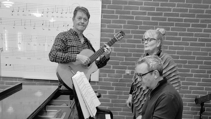 Musikere, der optræder sammen med en guitarist, pianist og sanger i et musiklokale.