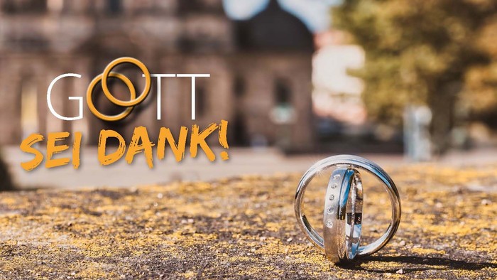 Zwei Eheringe sind ineinander verschlungen auf der Straße vor dem Dom zu sehen.