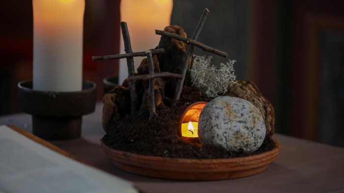 Geheimnisvoller Altaraufbau mit Kerzen, Zweigen und einer leuchtenden Kugel auf einem Holzbrett.