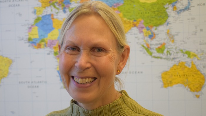 Kvinde med blond hår står foran worldmappe