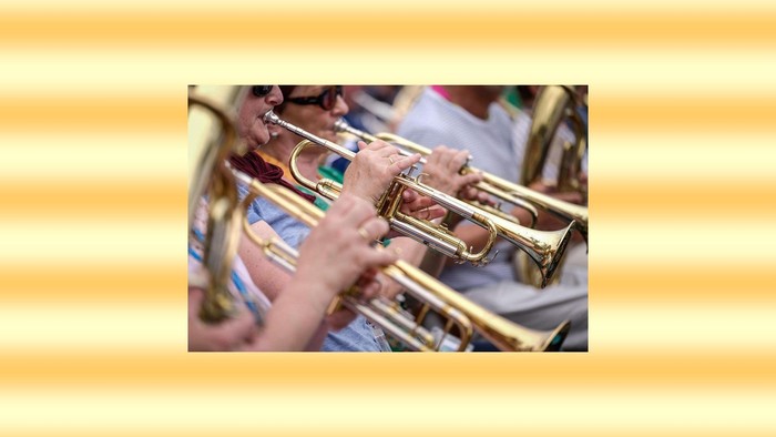 Das Bild zeigt Menschen die ein Blasinstrument spielen.