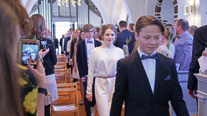 En gruppe ungdomme i formel klædning går i en kirke.