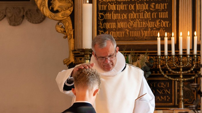 Præst konfirmerer mandlig konfirmand