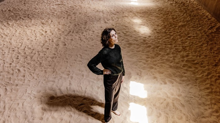 En person står selvsikkert i et rummeligt rum med sandlignende tekstureret gulv.