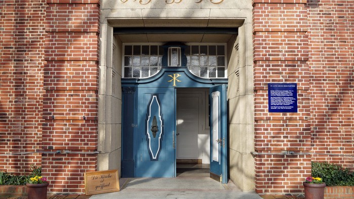 Eingang zu einem Gebäude mit blauer Tür und zwei Topfpflanzen