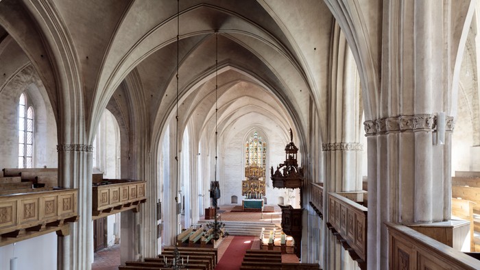Große, leere Kirche mit hohen Bögen und hölzernen Kirchenbänken.