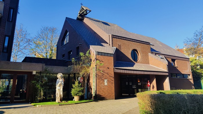 Et moderne kirkebygning med en statue foran og træer i baggrunden