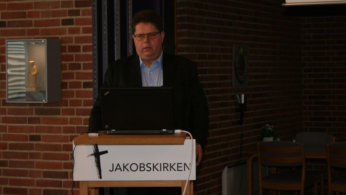 Mand ved pulpet med Jakobskirken skilt.