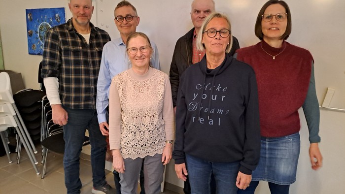 En gruppe af seks personer står sammen i et rum.