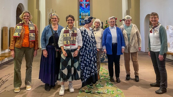 Acht Frauen tragen Teile bunter nigerianischer Tracht in einer Kirche