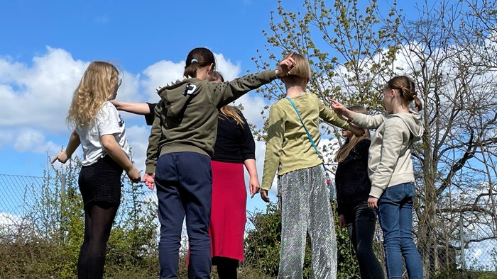 En gruppe af unge står sammen i en park og kigger op i træerne.