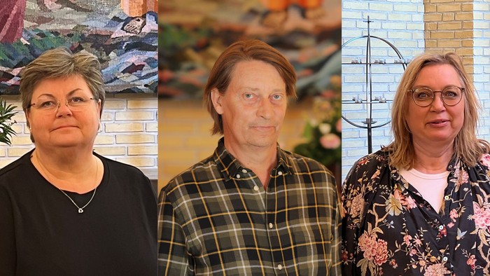 Tre personer poser til et portræt foran en dekoreret indendørs baggrund med blomster- og geometrisk kunst.