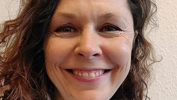 En glad kvinde med krøllet hår, der smiler til kameraet.