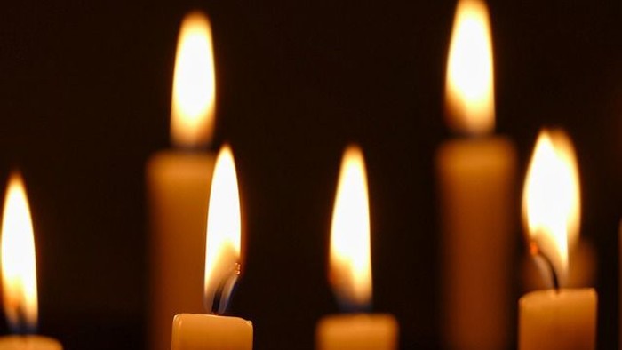 Mehrere brennende Kerzen vor dunklem Hintergrund