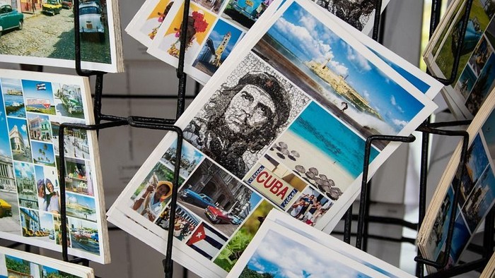 In einem Postkartenständer steht eine Postkarte aus Kuba. 