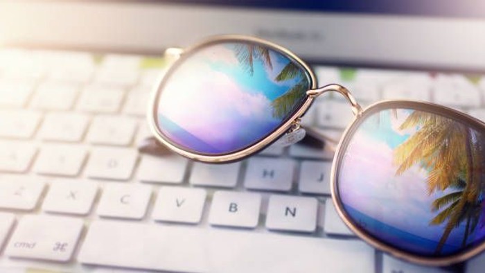 Sonnbrille auf Tastatur mit tropischem Reflex.