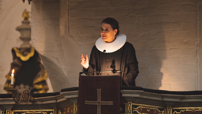 Ein Mann in priesterlicher Kleidung predigt an einem Pult in einer Kirche.