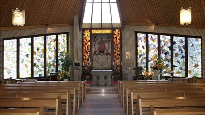 Die Kirche hat hölzerne Bänke und bunte Glasfenster.