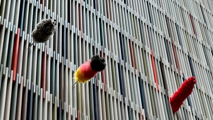 Zwischen den Holzlamellen der Altarrückwand schauen 3 Staubwedel hervor
