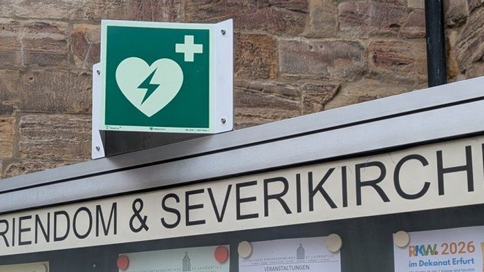 Schild vor dem Mariendom & der Severikirche, das auf einen in der Nähe verfügbaren automatisierten externen Defibrillator (AED) hinweist.