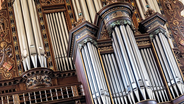 Indviklet pibeorgel med udsmykket træbeklædning og talrige sølvfarvede piber i en storslået arkitektonisk ramme.