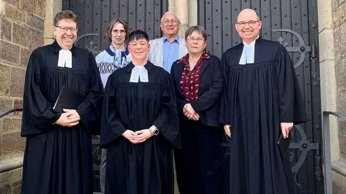 Laura Wessel (vorne, 2. von links) ist von Synodalassessor Karsten Malz (vorne links) in einem Gottesdienst zu ihrem Dienst als Prädikantin beauftragt worden.