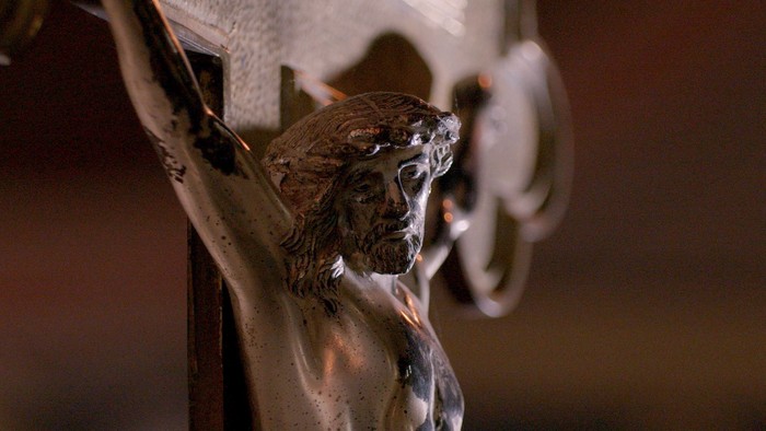 Eine silberne Jesus-Statue an einem Kreuz.