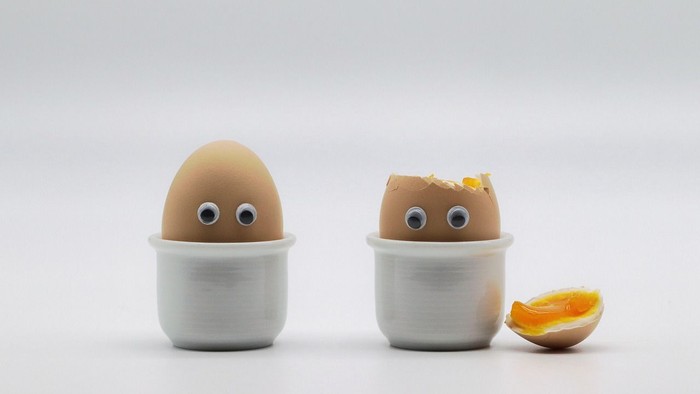 2 Frühstückseier mit aufgeklebten Augen, davon ist eines bereits aufgeschlagen.