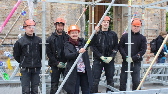 Eine Gruppe von Bauarbeitern in Sicherheitshelmen steht auf einer Baustelle.