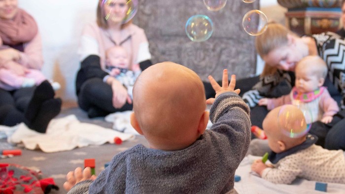 Børn spiller med boblebubbler og legetøj på gulv.