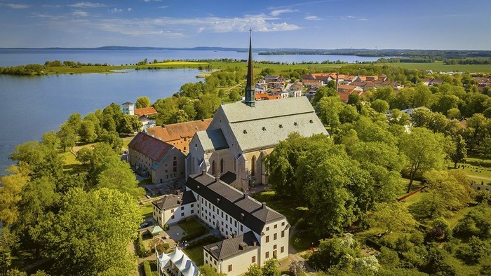 Luftfoto af en malerisk søby med en historisk kirke omgivet af frodig grønne områder og en vandkant.