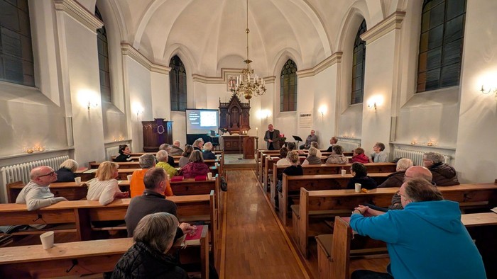 Gemeindeversammlung in der Kirche mit interessierten Besuchern und Leinwand