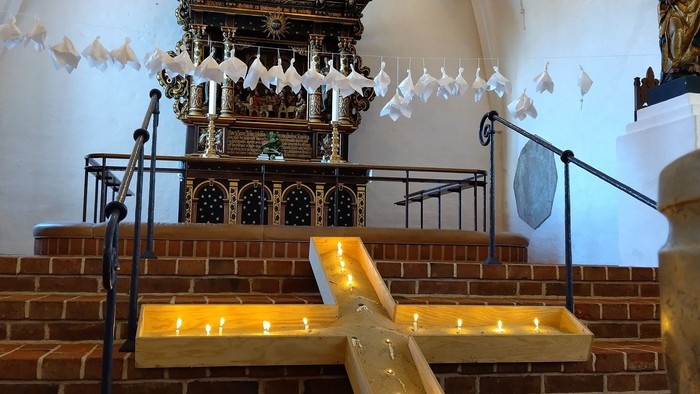 Elegant buet alter med prædikestol i udsmykket design, trappetrin med levende lys og hvide dueudsmykninger.