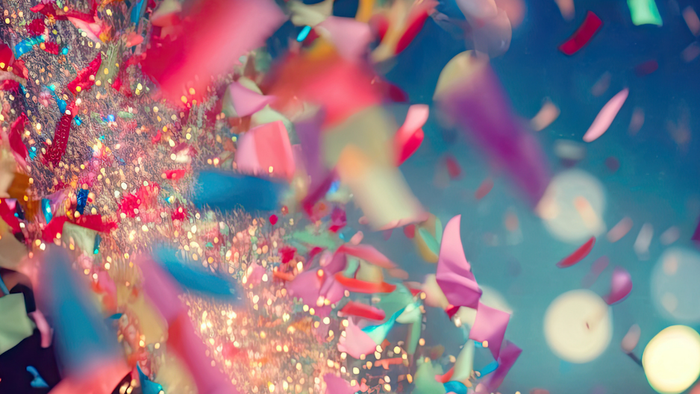 Bunte Konfetti und Glitzer wirbeln in einem lebhaften, festlichen Ausbruch vor einem tiefblauen Hintergrund.