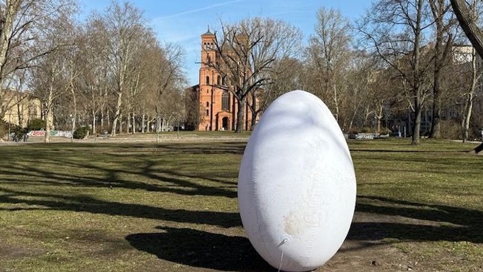Ein sehr großes weißes Oster-Ei steht im Park