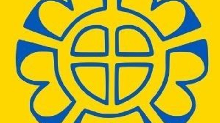 Ein stilisiertes Sonnenblumen-Emblem mit blauen Blütenblättern und einem gelben Zentrum, das ein Kreuzsymbol zeigt.