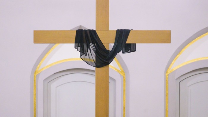 Kreuz mit schwarzem Tuch zwischen zwei weißen Bögen behangen