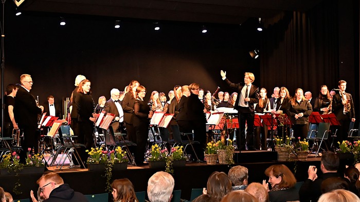 Orchester tritt auf der Bühne auf, während das Publikum aufmerksam zuschaut.