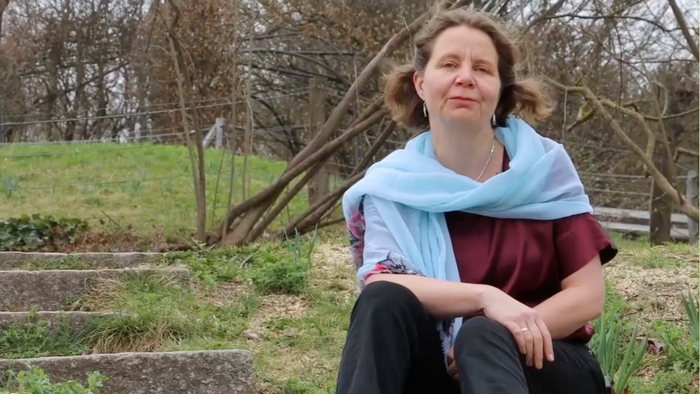 Pfarrerin Claudia Mieth auf einer Treppe in frühlingshafter Landschaft sitzend