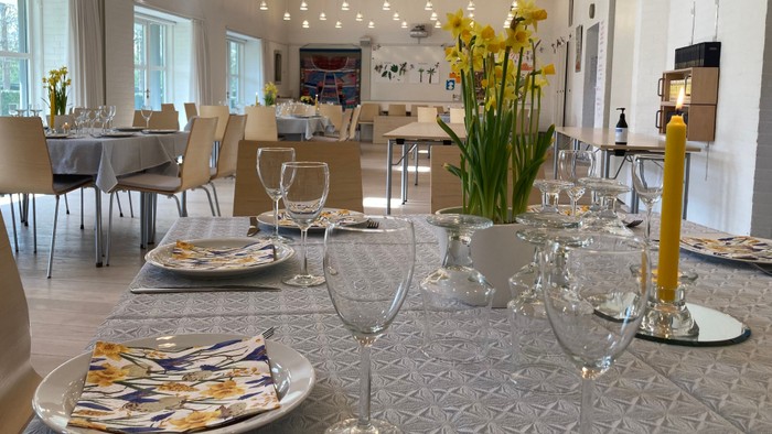 Påskedækket borde med duge, gule lys, påskeliljer, påskeservietter mv