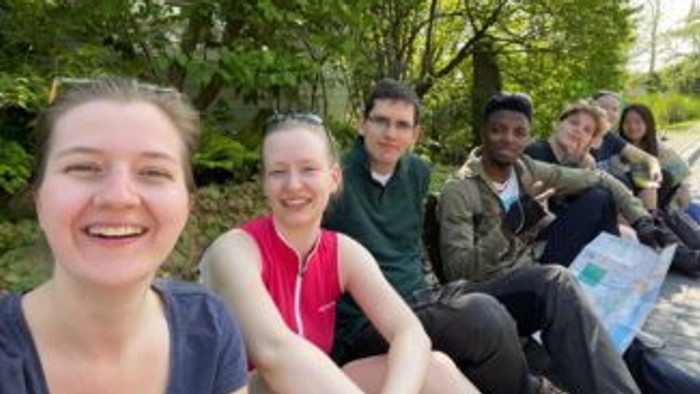 Eine Gruppe von Freunden, die glücklich im Freien in einer üppigen, grünen Waldlandschaft posieren.