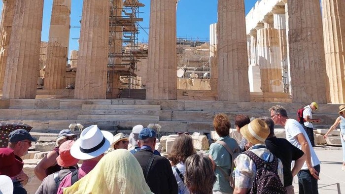 Touristen versammeln sich unter klarem Himmel am antiken Parthenon und betrachten seine imposanten Säulen und Ruinen.