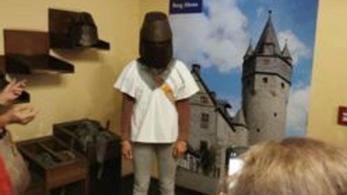Ein Kind steht an einer interaktiven Ausstellung mit einer mittelalterlichen Turmdarstellung, während andere zuschauen.