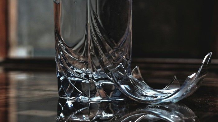 Eine zerbrochene Flasche auf einer glanzlackierten Tischplatte