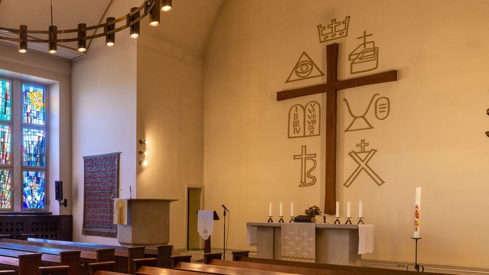 Elegante Kircheninnenausstattung mit hölzernen Kirchenbänken, Buntglasfenstern und einem zentralen Altarbereich.