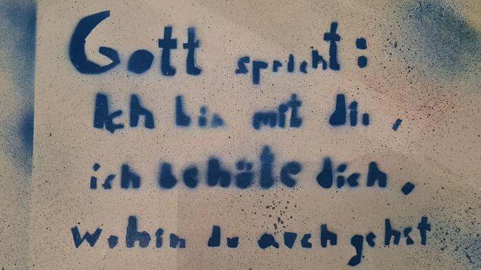 Bibelvers über Schutz und Bewahrung auf der Sitzfläche eines Stuhls im Foyer der Friedenskirche Offenbach: