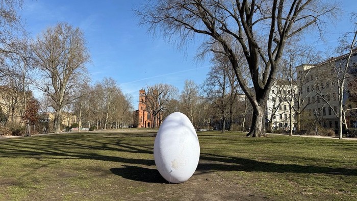 Ein sehr großes weißes Oster-Ei steht im Park
